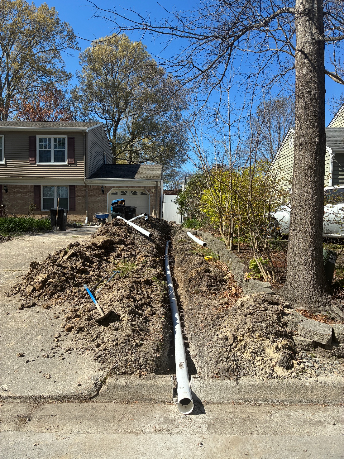 Long trench cut along a driveway for a residential drainage system