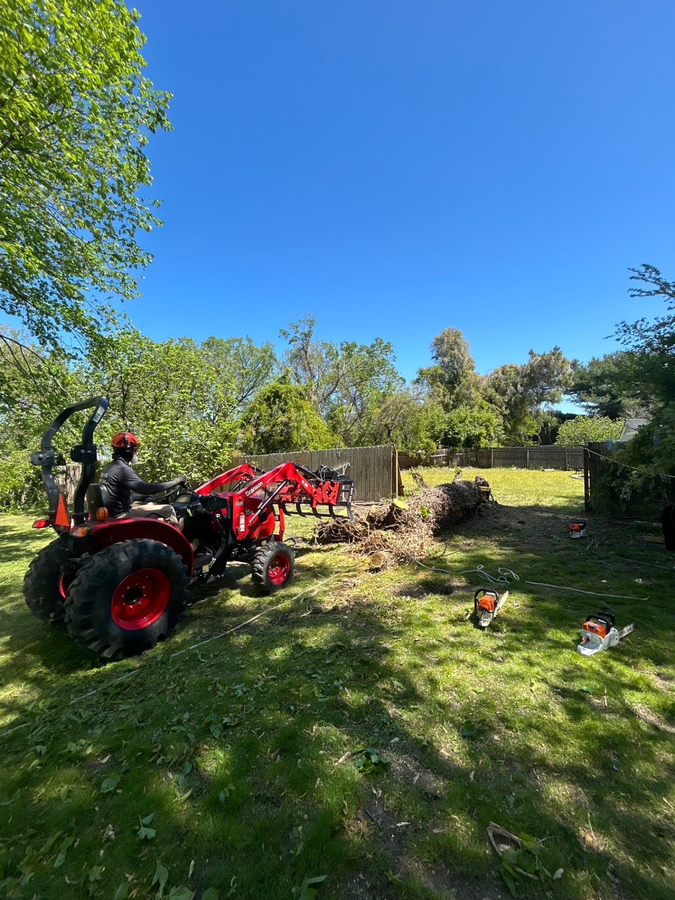 Compact tractor clearing a backyard during a landscaping and grading project